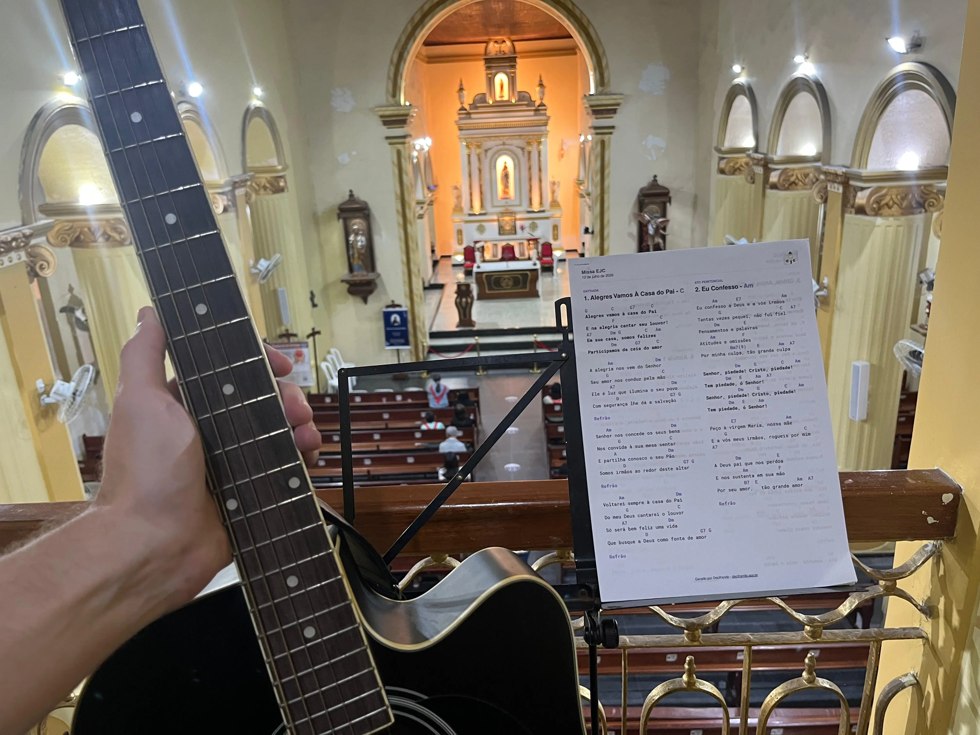 Músico com violão no coro da igreja, com o PDF do Decifrando na estante